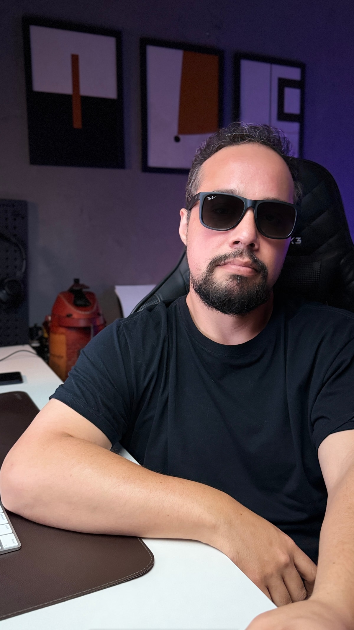 Éd Vieira de camiseta preta e óculos escuros, sentado à mesa